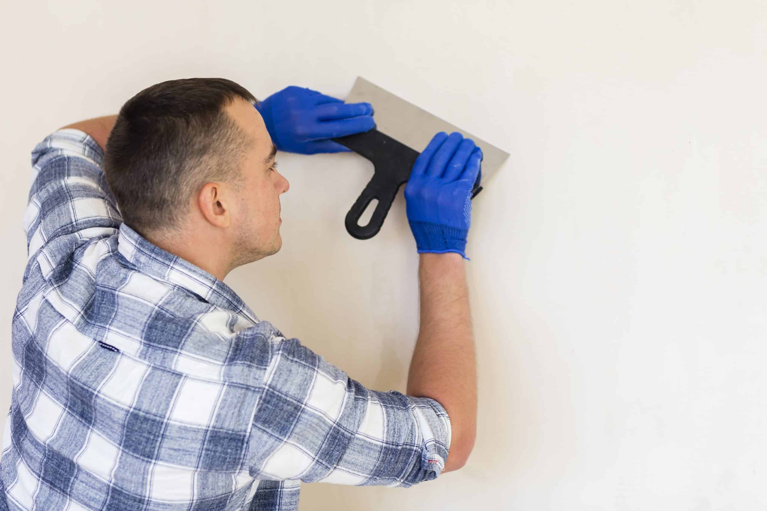 Worker troweling setting type joint compound onto a wall within its working-time window