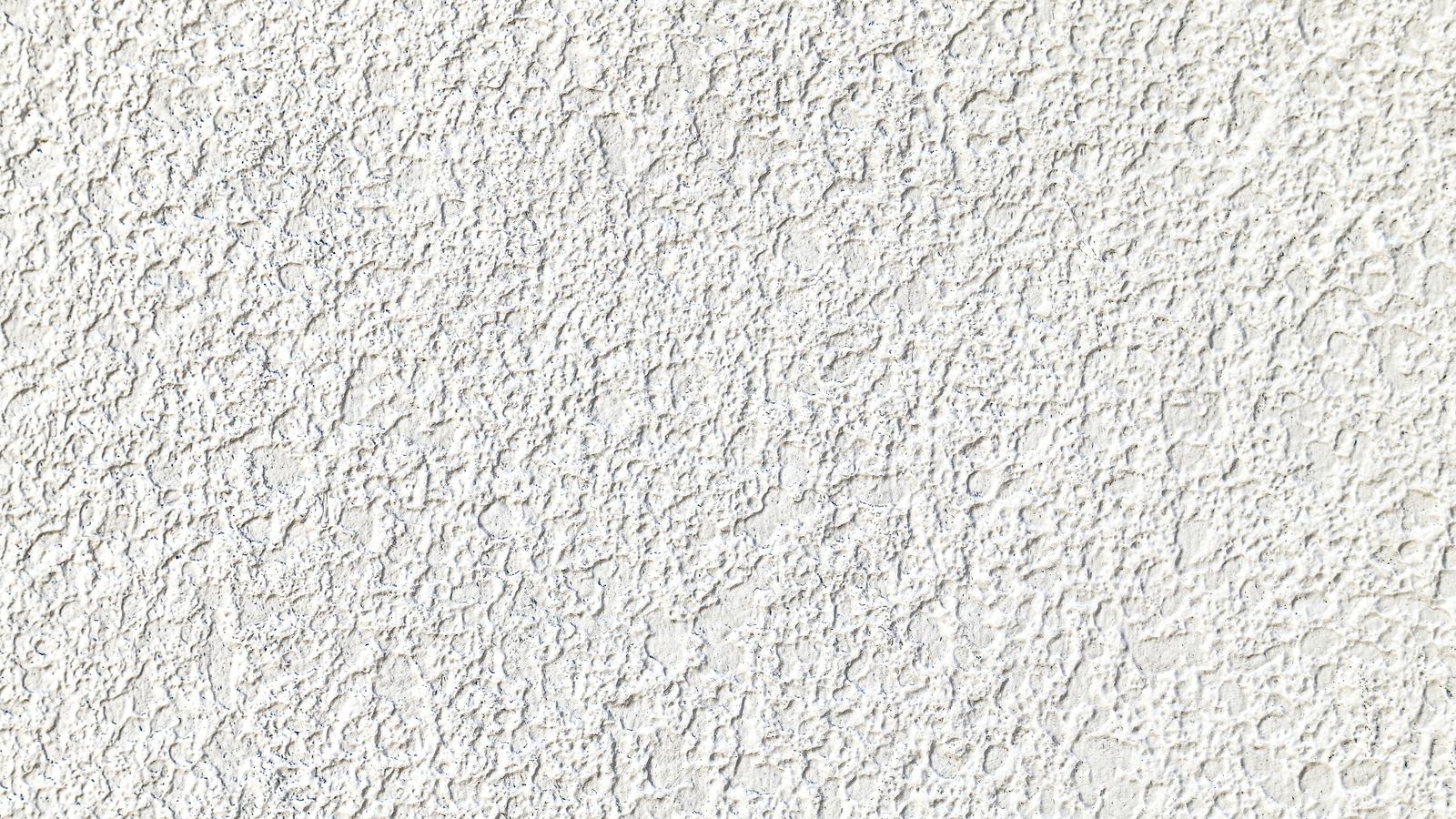 Close-up of heavy sprayed wall texture with raised peaks and valleys, the profile that decides whether wallpaper can go straight on